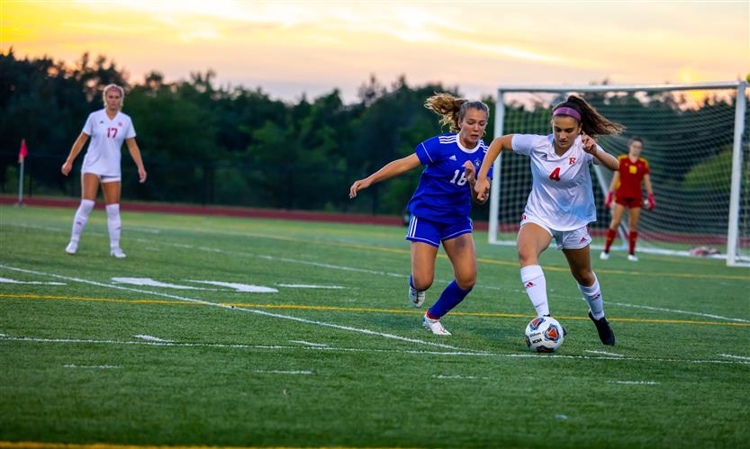 A soccer player dribbles around another player